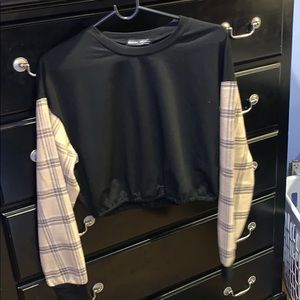 A black crop top with plaid sleeves
